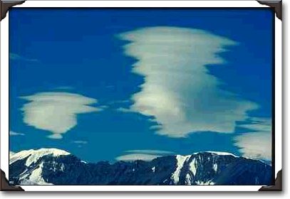 Clouds Between Trees And Mountain